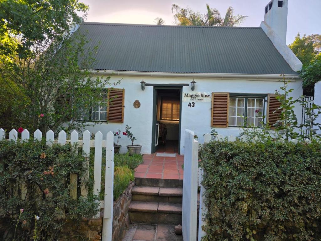 a white house with a white picket fence at Maggie Rose Cottage Self Catering in Greyton in Greyton