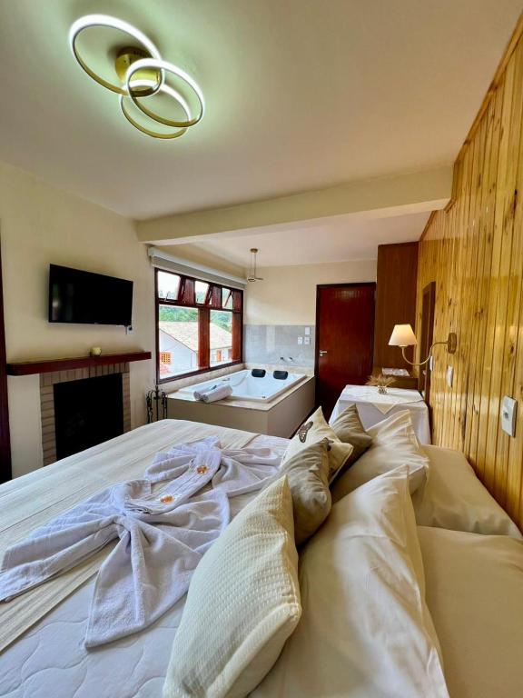 a large white bed in a bedroom with a fireplace at Casa Moreira´s Chalés in Monte Verde