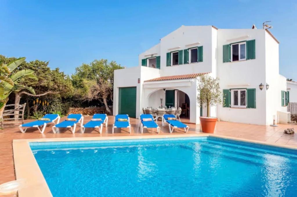 a villa with a swimming pool in front of a house at Villa Jultomas in Cala en Bosc