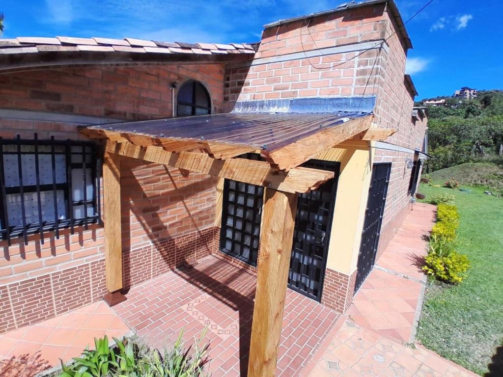 an outdoor wooden pergola attached to a brick building at Villa El Colibri in El Peñol