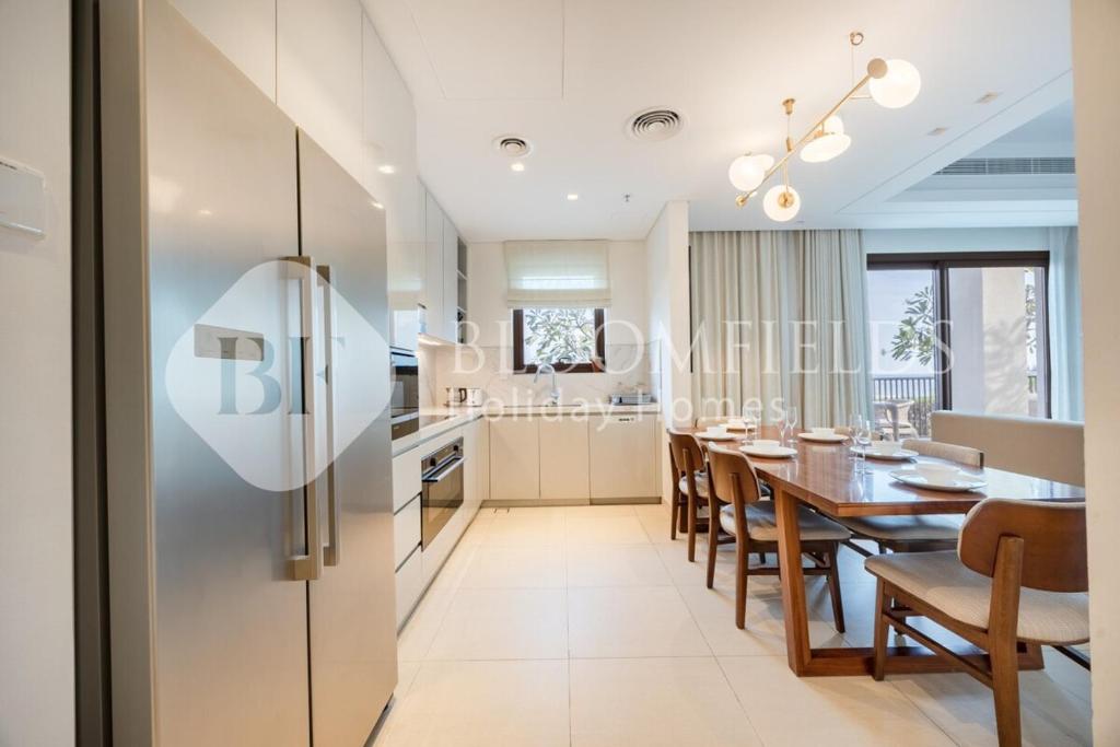 a kitchen and dining room with a table and a refrigerator at Bloomfields 3BR - Address Residences Fujairah in Fujairah