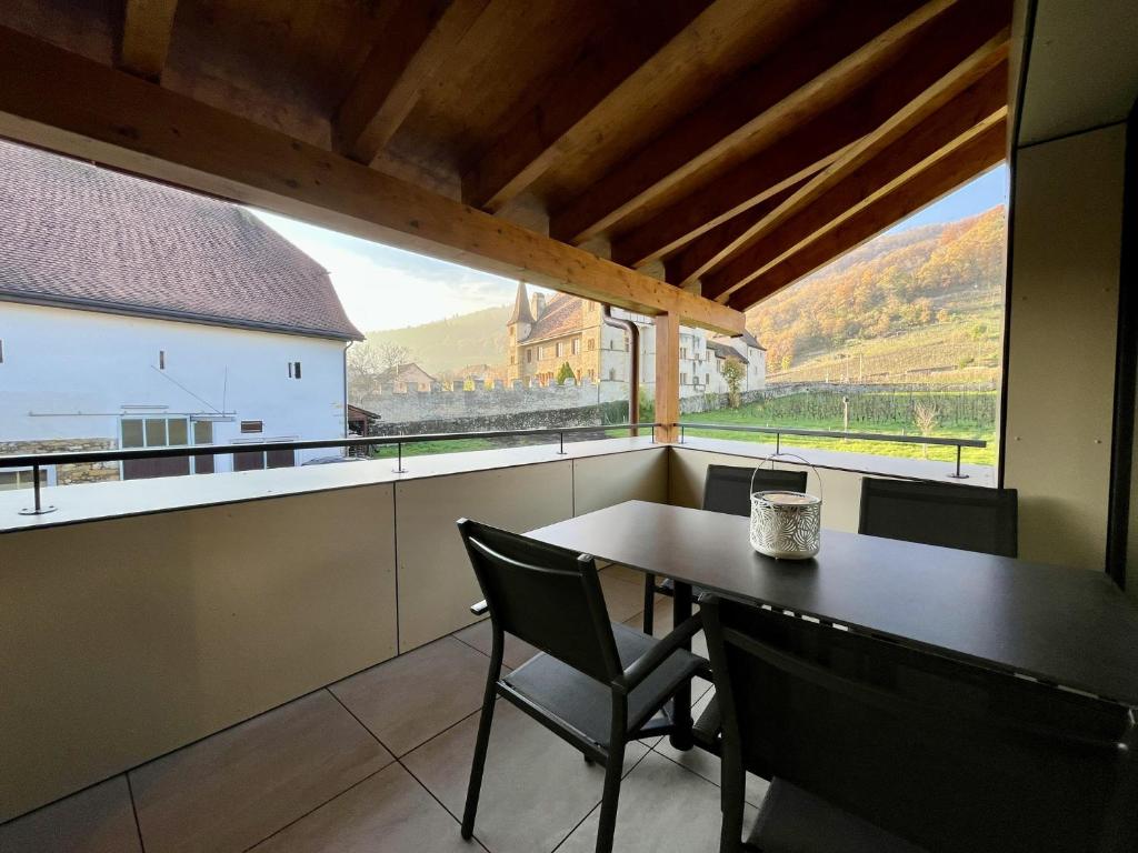 une salle à manger avec une table et des chaises et une grande fenêtre dans l'établissement Terrasse des vignes, à Cressier
