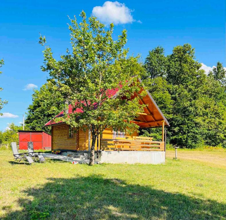 una baita di tronchi con un albero in un campo di Brvnara Duga njiva a Čelinac