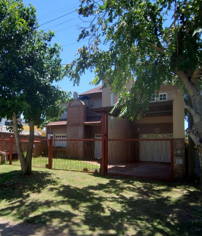 a house with a fence and a tree at Amanece en la playa 2 in Santa Teresita