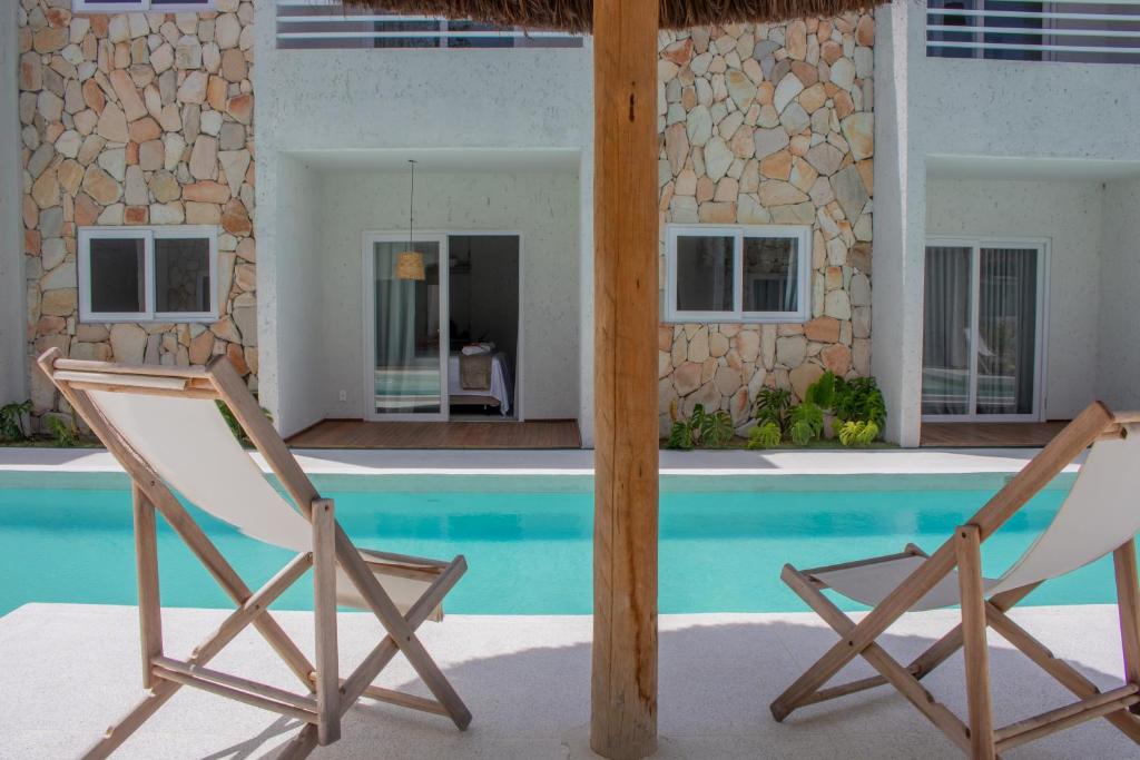 a pair of chairs next to a swimming pool at Apartamentos Curimã in Passo de Camarajibe
