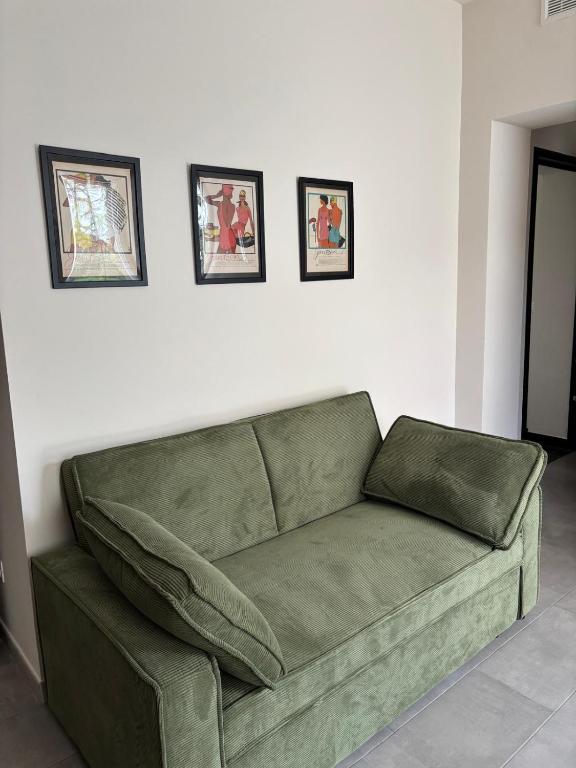 ein grünes Sofa vor einer weißen Wand mit drei Bildern in der Unterkunft villa Pieri appartamento black in Fauglia