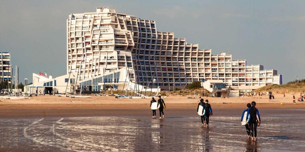 een groep mensen die op het strand lopen met surfplanken bij Saint jean de monts in Saint-Jean-de-Monts