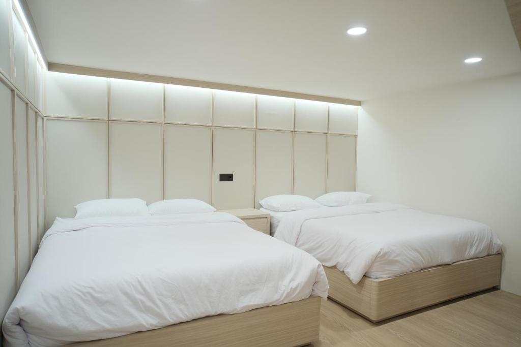 two beds in a room with white walls at INSAHAUS Guest House in Kotalama