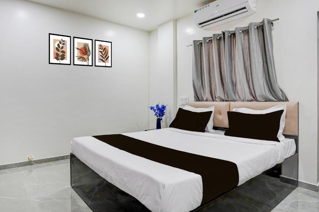 a bedroom with a large white bed with black pillows at HOTEL O THE COZY INN in Sakardarā