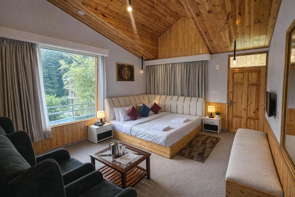 a bedroom with a bed and a large window at Apple Flower Mountain View Hotel in Manāli