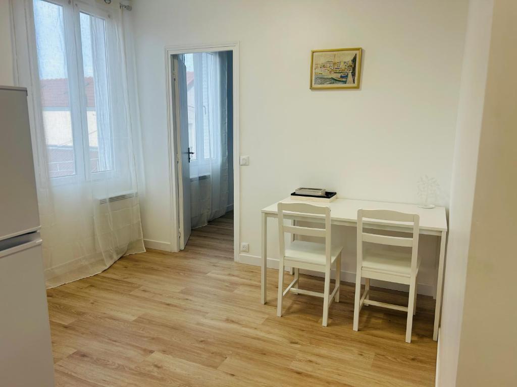 einen weißen Tisch und Stühle in einem weißen Zimmer in der Unterkunft Renovated prestige apartment in Aubervilliers