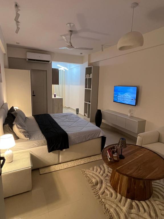 ein Schlafzimmer mit einem Bett und einem Fernseher an der Wand in der Unterkunft The Elysian in Ghaziabad