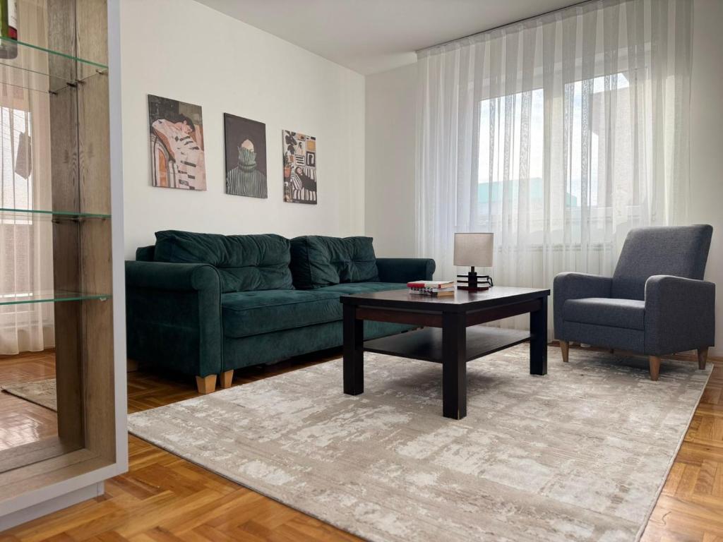 een woonkamer met een groene bank en een tafel bij Odmori se, Centar apartman in Donje Mladice