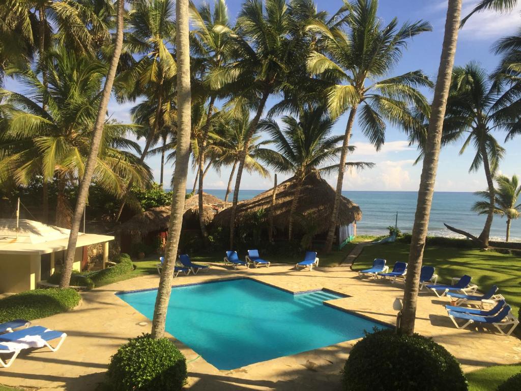 uma piscina de resort com palmeiras e o oceano em La Punta Apartamentos em Cabarete