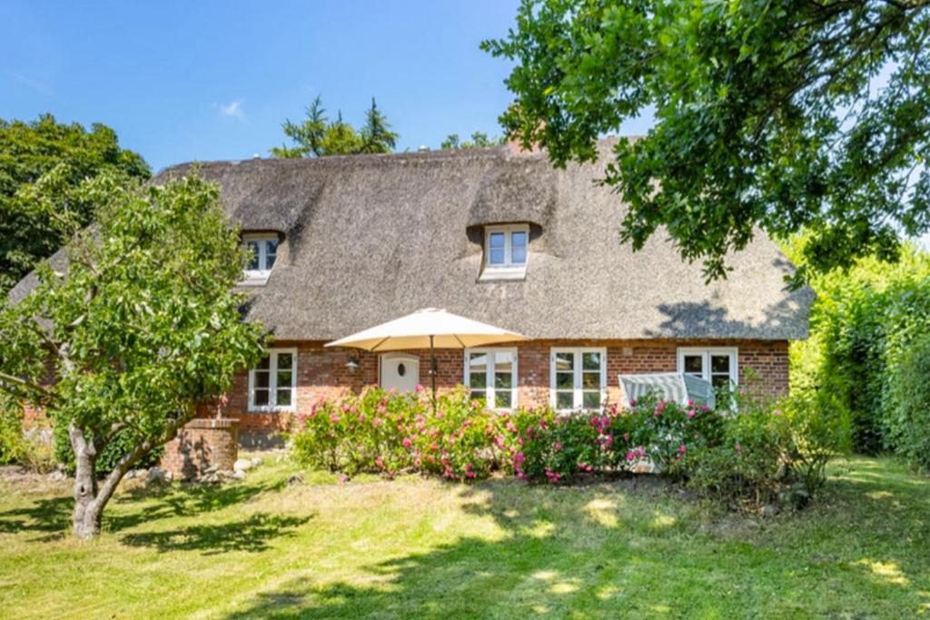 a brick house with a thatched roof at Lüttje Huus 1875 in Struckum