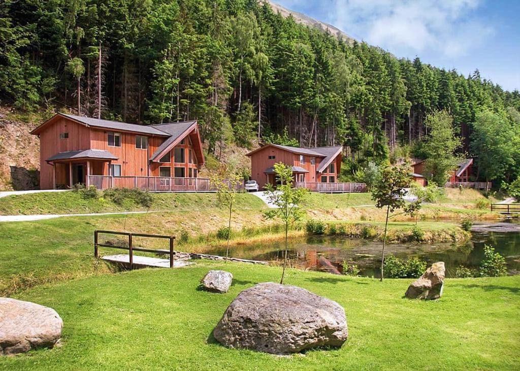 een hut in de bergen met een vijver en rotsen bij Penvale Lakes Lodges in Llangollen