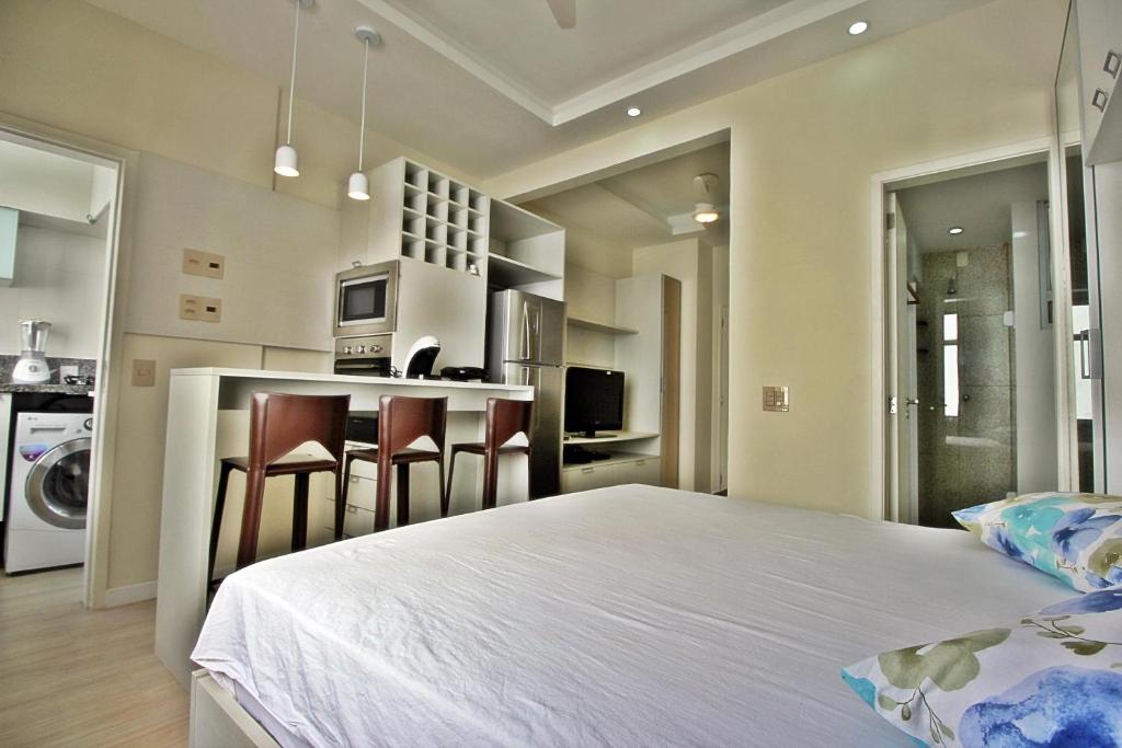 a bedroom with a large white bed and some chairs at Rio Spot Ipanema C011 in Rio de Janeiro