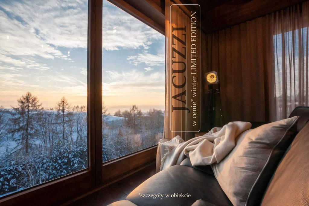 Una habitación con una ventana con un sofá y un libro. en GÓRSKIE KLIMATY slowtravel - miejsce z klimatem - drewniany dom premium z viewpoint na panoramę Tatr ecoSPA strefa fitness ZIELONA FARMA healinggarden - exp kozauwoza, en Szlembark
