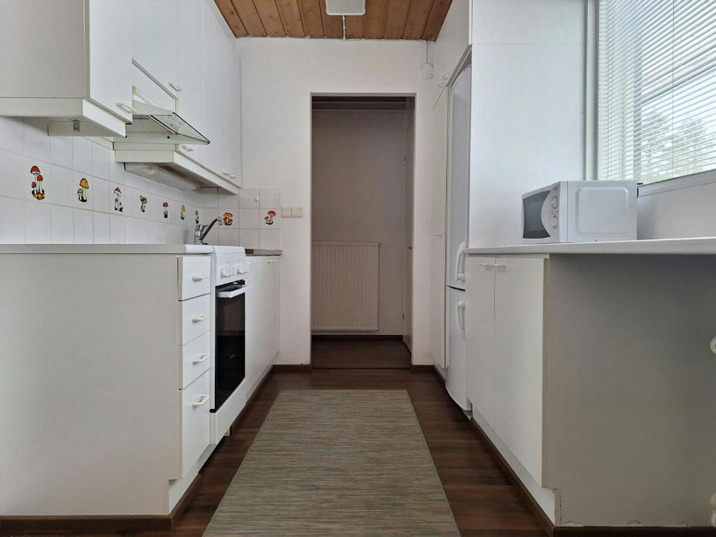 a kitchen with white cabinets and a microwave at Spacious Apartment for 5 in Sodankylä