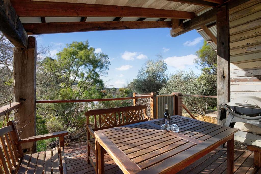 a wooden table on a deck with a grill at Leura Haven Rustic Mountain Cottage in Leura