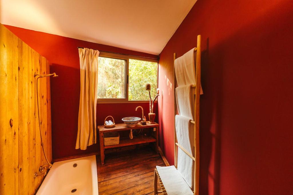 Oasis Garden Marrakech في مراكش: حمام ذو جدران حمراء ونافذة وحوض استحمام