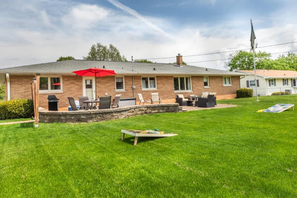 a house with a yard with a table and an umbrella at Stadium District Resch 3 BR Sleeps 8 in Green Bay