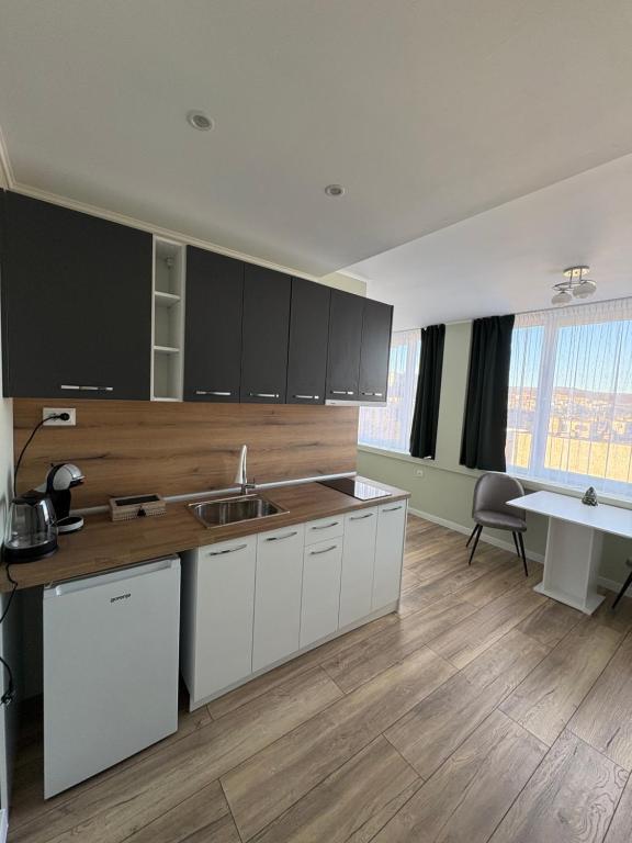 a kitchen with white cabinets and a wooden floor at Atelier SkyLine in Gabrovo