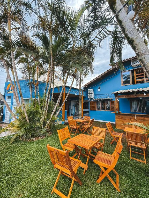a group of wooden tables and chairs in front of a building at Sea Wolf Surf Hostel Campeche in Florianópolis