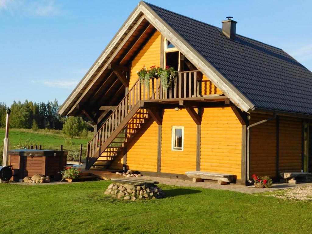 eine große gelbe Hütte mit einem Balkon und einer Terrasse in der Unterkunft Vecvanagi in Jaunmuiža