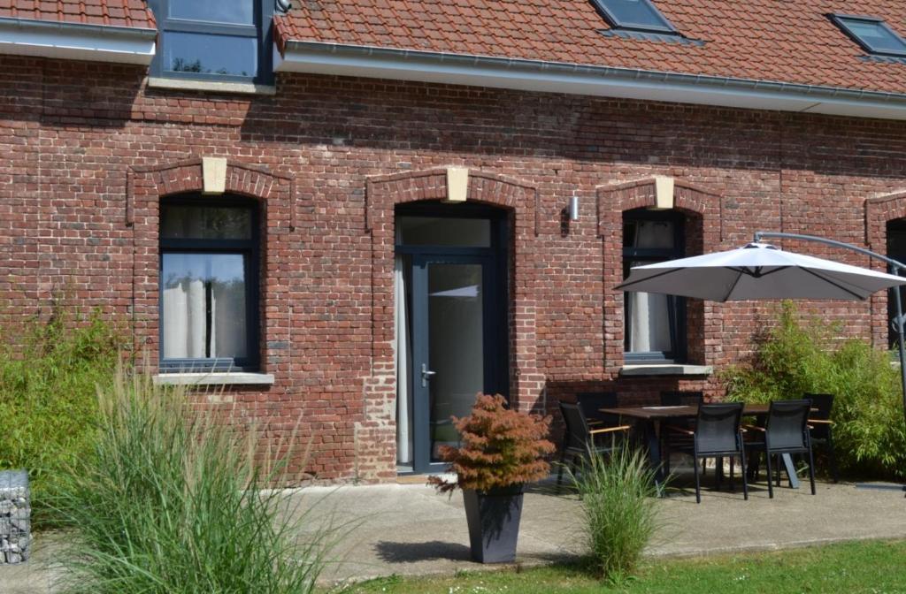 un edificio in mattoni con tavolo e ombrellone di Gite Clémentine a Baromesnil