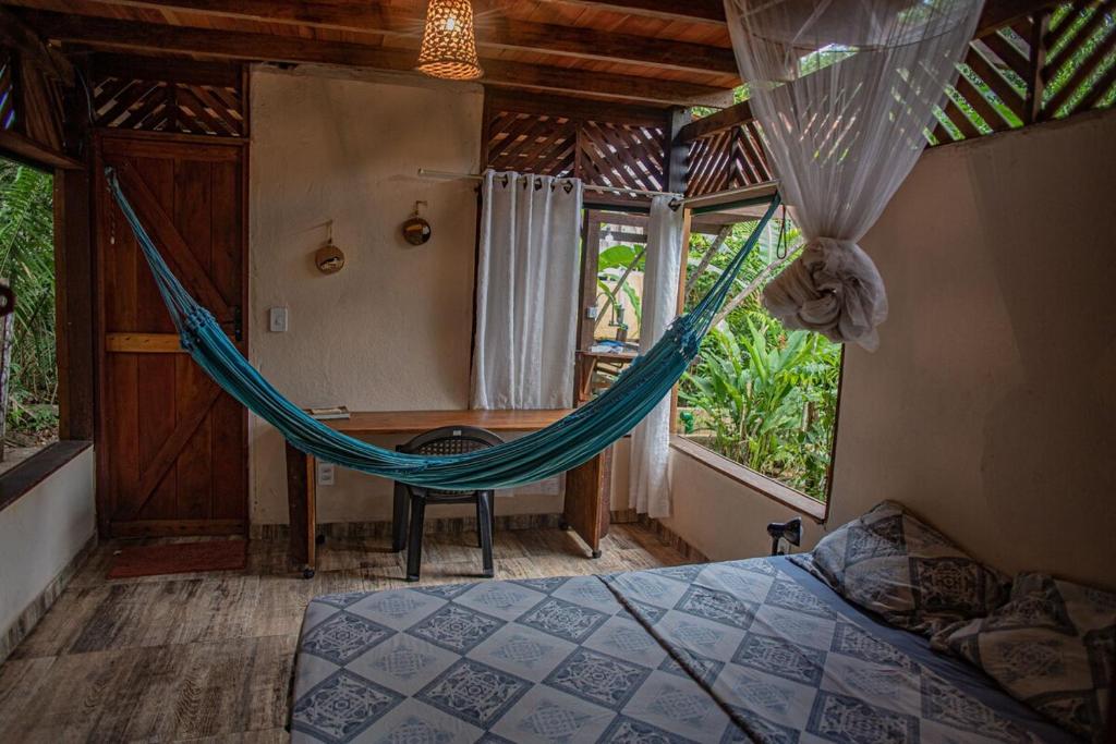 a hammock in a room with a bed and a desk at Bangalôs Suítes na Floresta Encantada in Santarém
