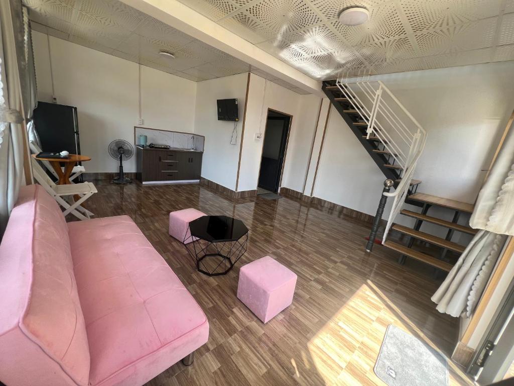 a living room with a pink couch and a staircase at Mia Homestay and Coffee in Bảo Lộc