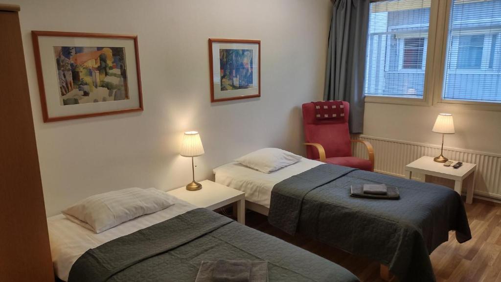 una stanza d'albergo con due letti e una sedia di Hotel 24 - Apartments a Kemi