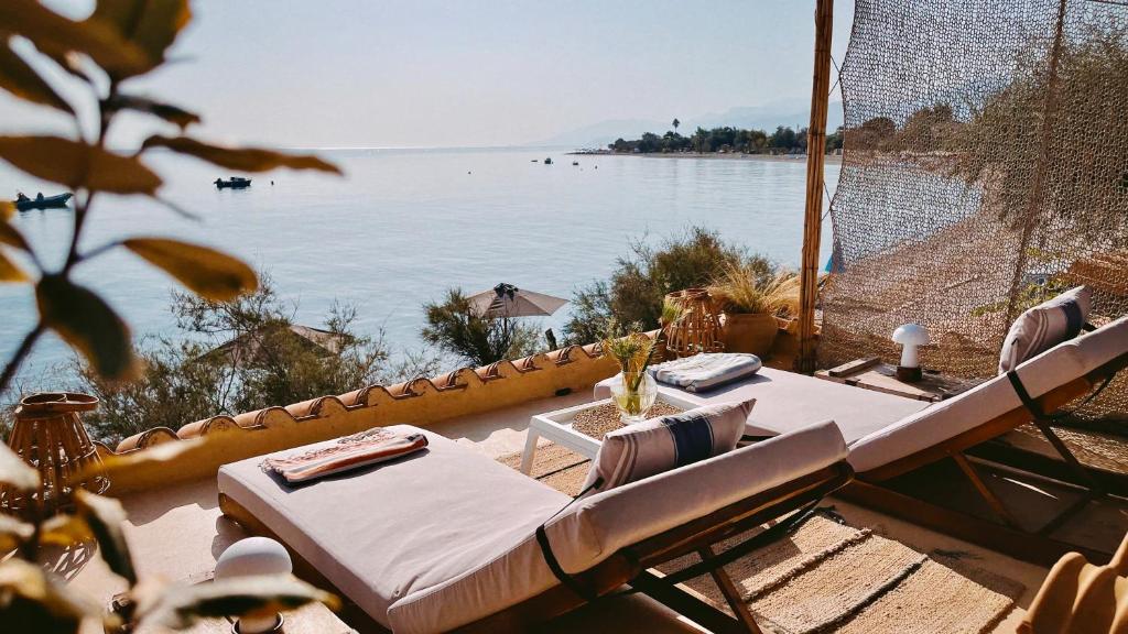 een tafel en stoelen met uitzicht op het water bij The Artist's Farm in Dhiyeliótika