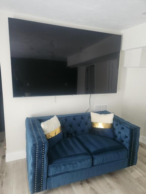 een blauwe bank met 2 kussens in de woonkamer bij Modern Basement Suite • King Bed & 100” TV in Shrewsbury