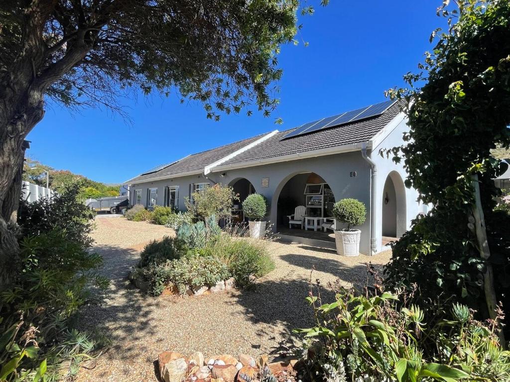 een wit gebouw met een tuin met planten bij Kommetjie Mountain Oasis in Kommetjie