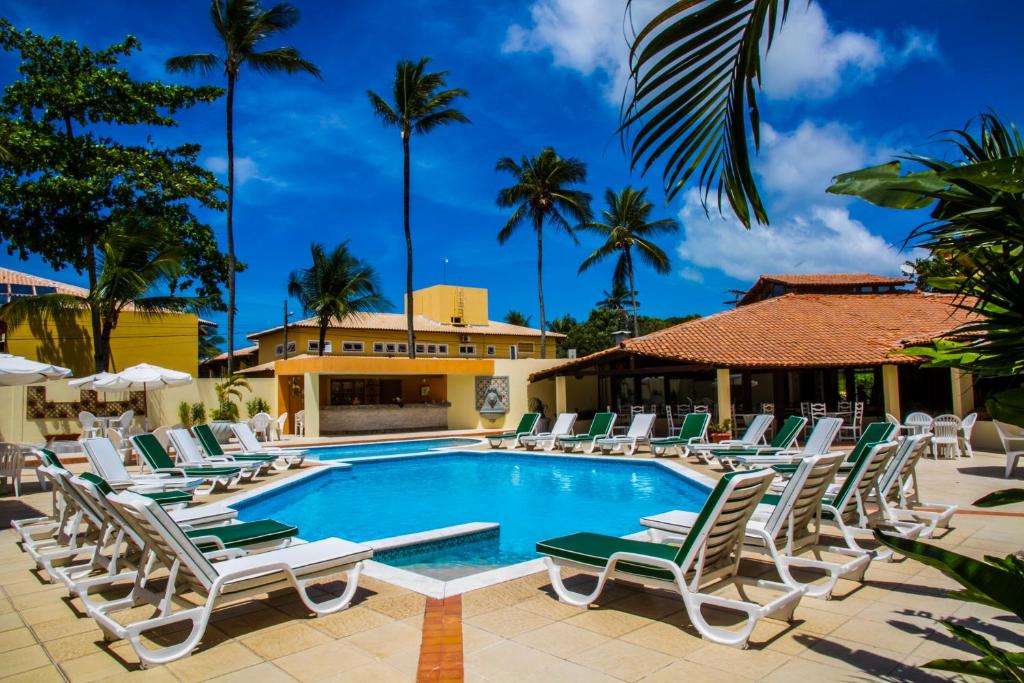 una piscina con tumbonas y palmeras en Happy Hotel Girassol, en Porto Seguro