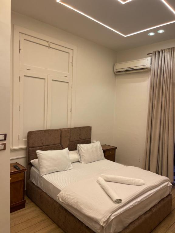 a bedroom with a large bed with white sheets at Miami Hotel in Cairo