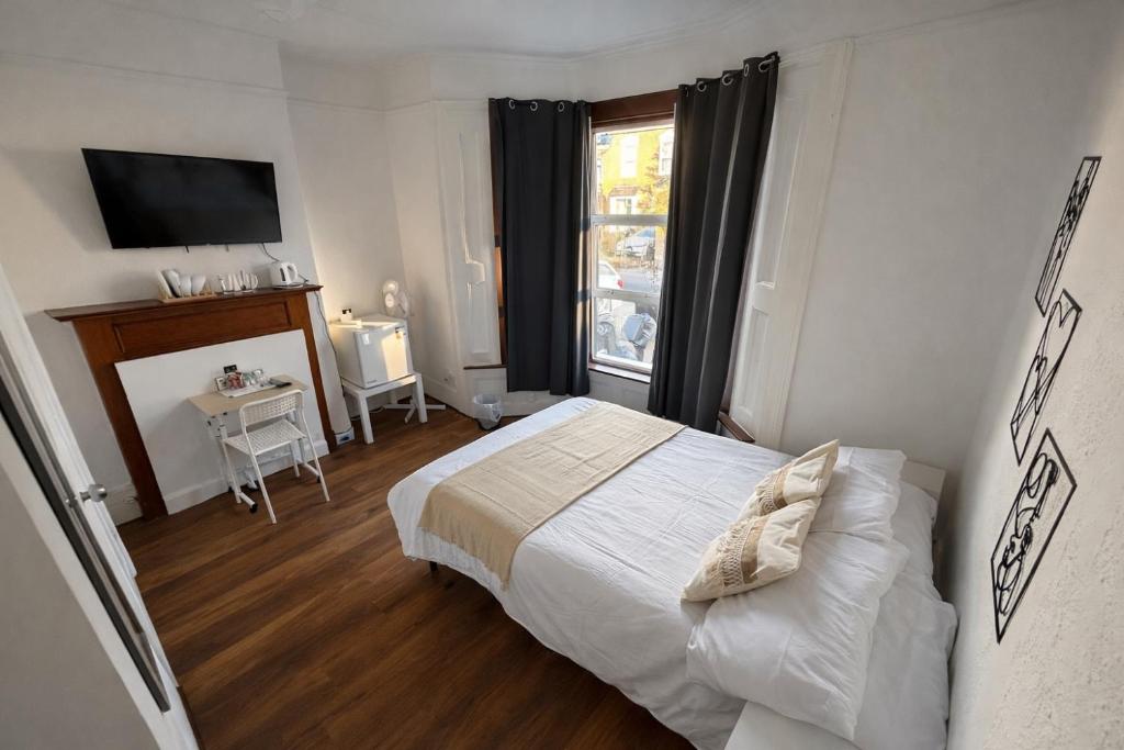 une chambre avec un lit blanc et une fenêtre dans l'établissement 43 Deluxe London Ensuites, à Londres