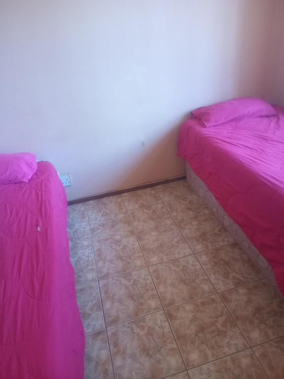 two beds in a room with a tile floor at Sleep Well in Amanzimtoti
