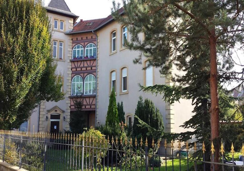 een groot huis met een hek ervoor bij Le Jardin de Phanie, le calme de la campagne en ville in Metz