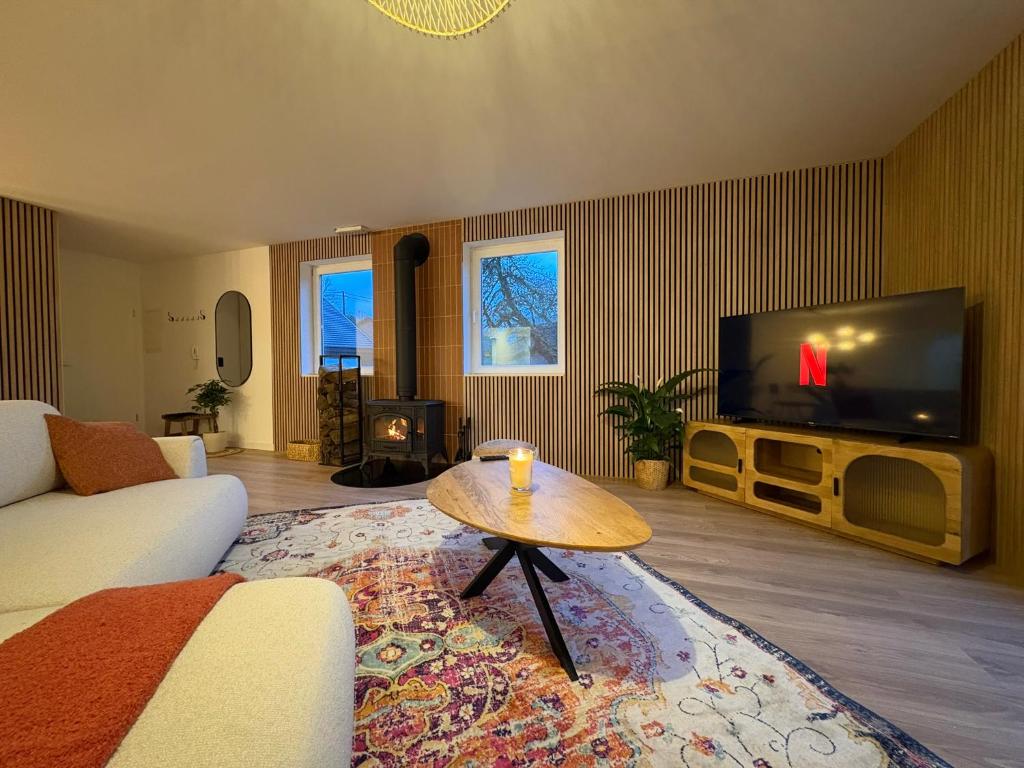een woonkamer met een bank, een tv en een tafel bij Le lofty in Stoumont
