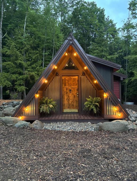 a cabin with a porch with lights on it at Trekker, Treehouses cabins and lodge rooms in Lake George
