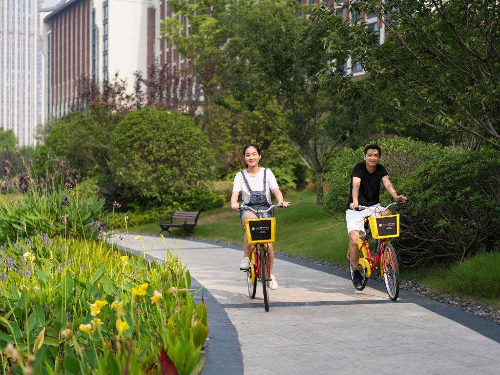 dos personas montando bicicletas por un camino en un parque en Pullman Hefei Sunac, en Hefei