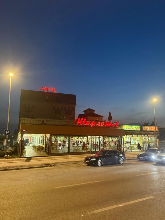 a street with cars parked in front of a store at Hotel Sharlota in Skopje