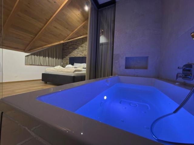 eine große blaue Badewanne in einem Zimmer mit einem Bett in der Unterkunft Vila Vento in Veľký Slavkov