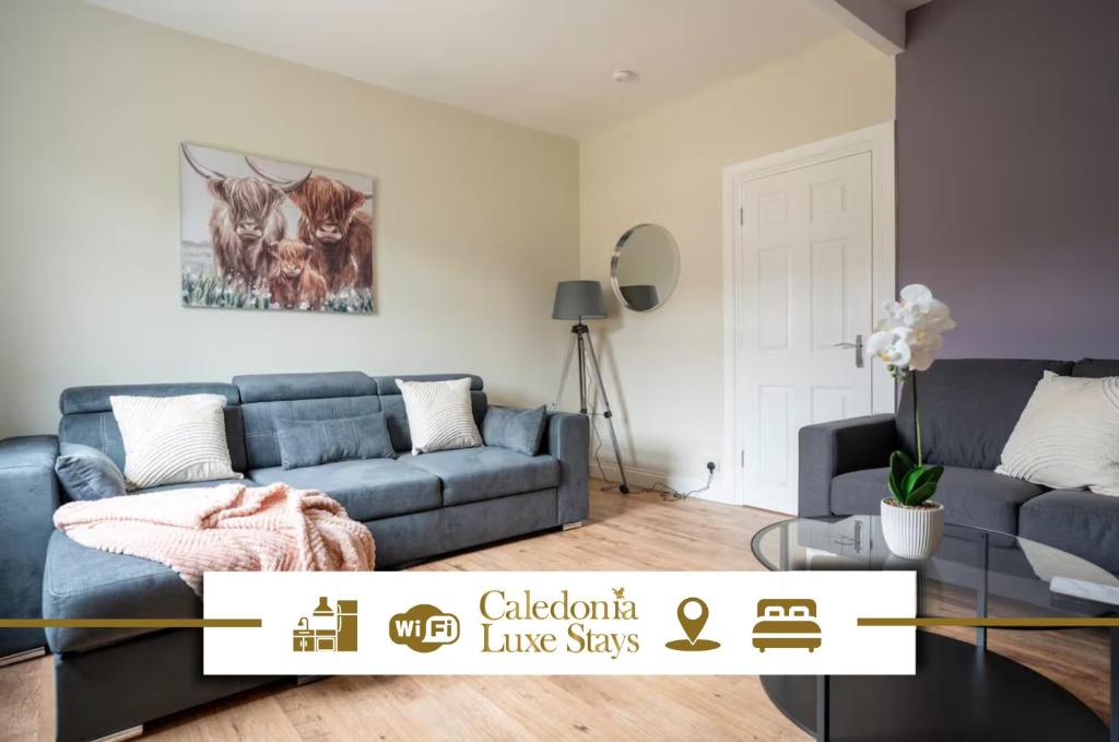 een woonkamer met een blauwe bank en een tafel bij 3 BDR House At Caledonia Luxe Stays Short Lets & Serviced Accommodation Dunfermline in Dunfermline