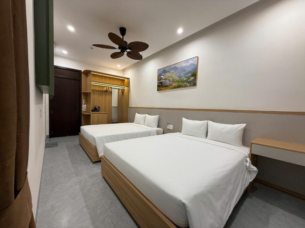 um quarto de hotel com 2 camas e uma ventoinha de tecto em Bacnam Quang Ngai Hotel em Kon Rung (1)