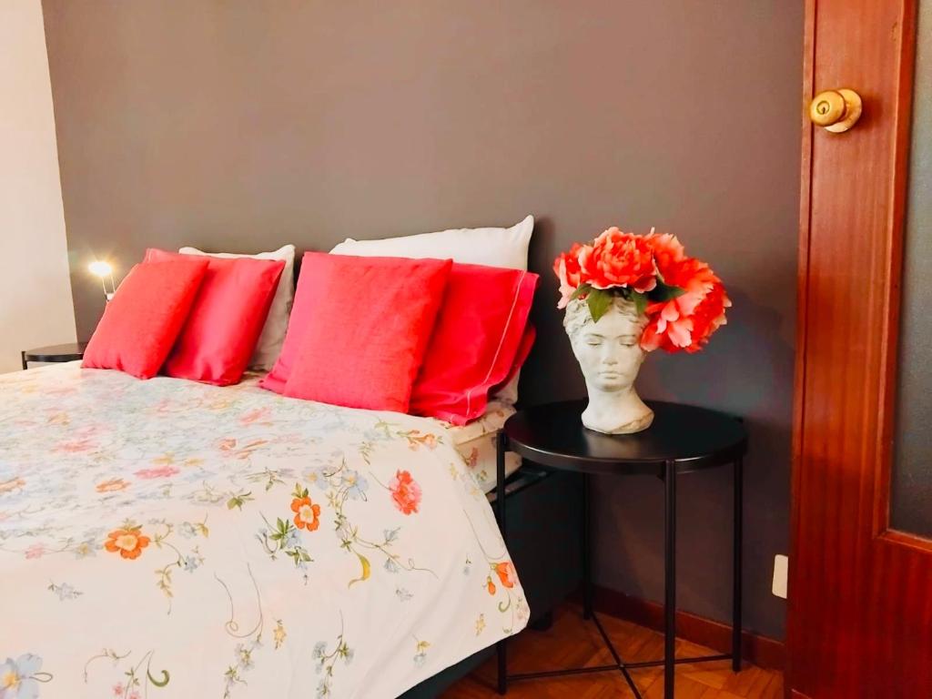 een bed met rode kussens en een vaas met bloemen op een tafel bij Charming Central Relais in Bergamo