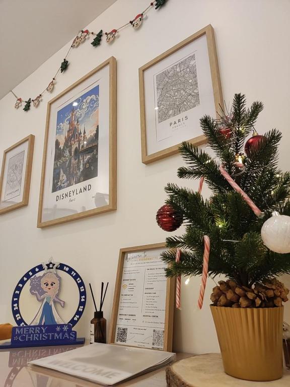un sapin de Noël sur une table avec des images accrochées au mur dans l'établissement La Maisonnette - Disneyland Paris, à Chanteloup-en-Brie
